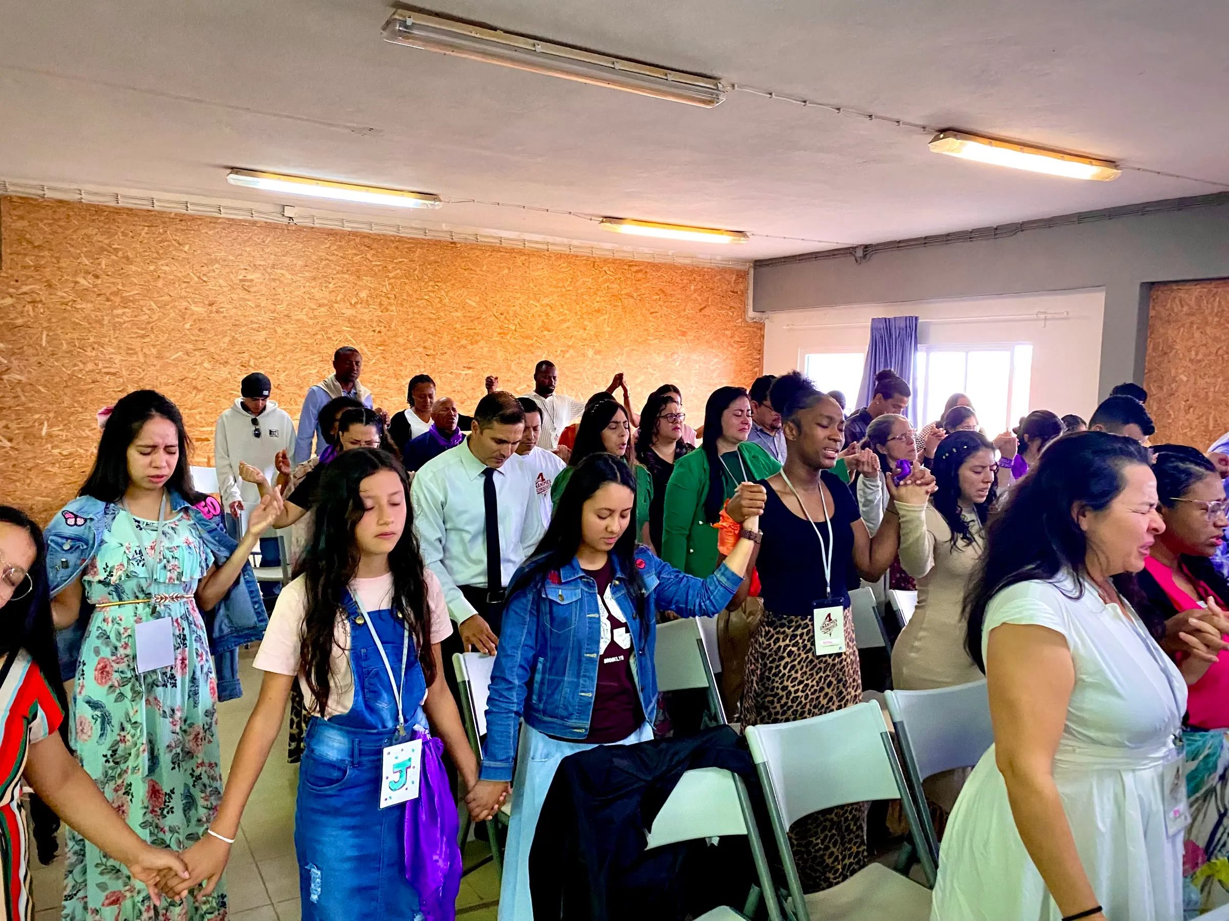 Pessoas de todas as idades a orar de mãos dadas no acampamento anterior